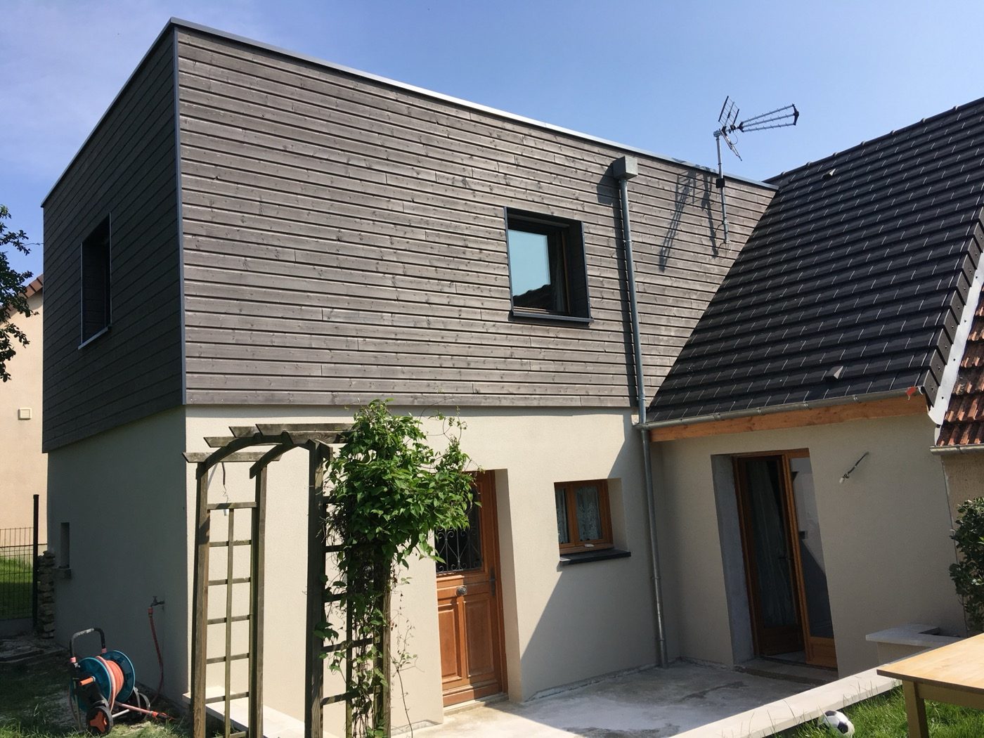 Extension à bardage gris foncé adossée à une maison existante, Bati M2G